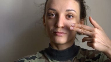 Genç kız, Ukrayna 'da zorunlu askerlik üniforması ve eşitlik kavramlarıyla parmaklarını kullanarak yanağında mavi ve sarı Ukrayna bayrağı taşıyor.