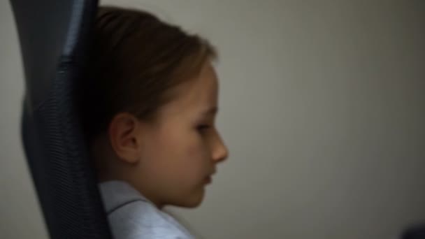 Little sad girl is sitting on black office chair, punishment, serious face — Stock Video