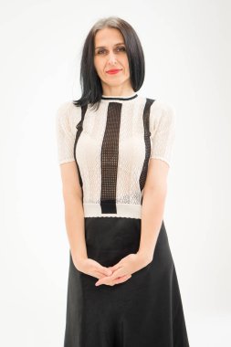 Stüdyo fotoğrafında orta yaşlı bir kadın beyaz arka planda siyah beyaz elbiseler giyerek saçlarını ağartmaya başlıyor. Orta yaşlı seksi kadın, mutlu yaşam kavramı.