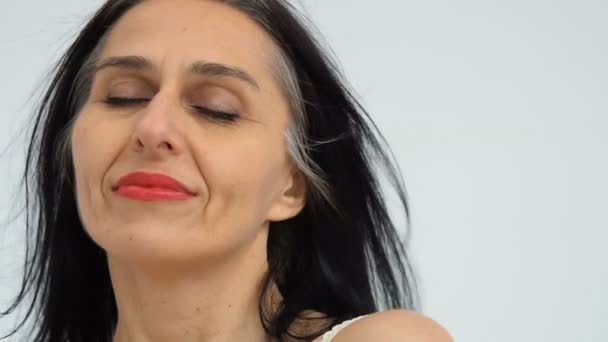 Frauenporträt einer Frau mittleren Alters, die im Studio beginnt, grauhaarig zu werden, mit nackten Schultern auf weißem Hintergrund, Gesichtspflege Schönheit, Hautpflege mittleren Alters Kosmetik, Kosmetikkonzept — Stockvideo