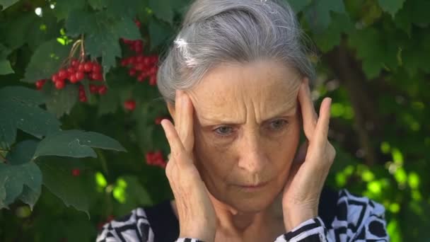 Unavená starší šedovlasá žena se cítí špatně kvůli menopauze, menopauze konceptu úlevy stojí u zeleného stromu — Stock video