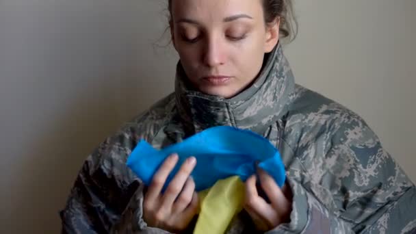 Giovane soldato donna tiene bandiera ucraina con amore e ansia a causa di escalation conflitto militare da parte della parte occidentale dell'Ucraina, invasione russa, concetto di guerra — Video Stock