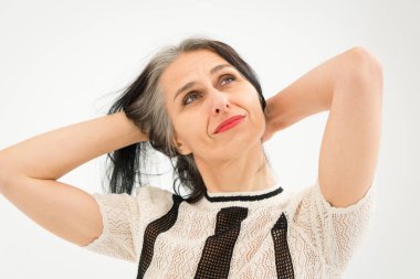 Stüdyo fotoğrafında orta yaşlı bir kadın beyaz arka planda siyah beyaz elbiseler giyerek saçlarını ağartmaya başlıyor. Orta yaşlı seksi kadın, mutlu yaşam kavramı.