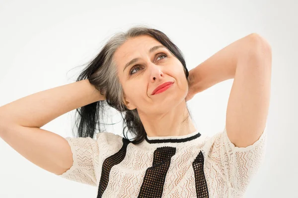 Stüdyo fotoğrafında orta yaşlı bir kadın beyaz arka planda siyah beyaz elbiseler giyerek saçlarını ağartmaya başlıyor. Orta yaşlı seksi kadın, mutlu yaşam kavramı. — Stok fotoğraf