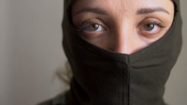 Haki kar maskesi giyen genç bir kızın kadın portresi, sadece gözler görünür, zorunlu askere alınma, askerlik, feminizm, eşitlik kavramı