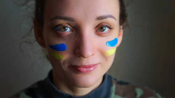 Retrato interior de niña con bandera ucraniana azul y amarilla en la mejilla con uniforme militar, reclutamiento obligatorio en Ucrania, conceptos de igualdad —  Fotos de Stock