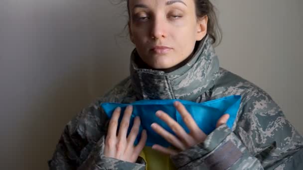 Giovane soldato donna tiene bandiera ucraina con amore e ansia a causa di escalation conflitto militare da parte della parte occidentale dell'Ucraina, invasione russa, concetto di guerra — Video Stock