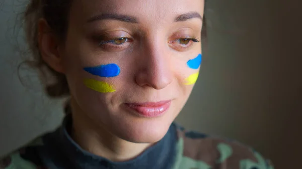 Retrato interior de niña con bandera ucraniana azul y amarilla en la mejilla con uniforme militar, reclutamiento obligatorio en Ucrania, conceptos de igualdad —  Fotos de Stock