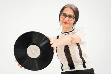 Stüdyo fotoğrafında orta yaşlı bir kadın gri saçlı, siyah beyaz giysili, plastikten plaklı beyaz elbiseli orta yaşlı, seksi bir kadın, mutlu bir hayat konsepti var.