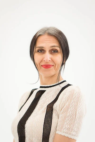 Stüdyo fotoğrafında orta yaşlı bir kadın beyaz arka planda siyah beyaz elbiseler giyerek saçlarını ağartmaya başlıyor. Orta yaşlı seksi kadın, mutlu yaşam kavramı.