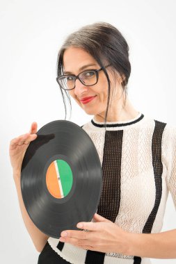 Stüdyo fotoğrafında orta yaşlı bir kadın gri saçlı, siyah beyaz giysili, plastikten plaklı beyaz elbiseli orta yaşlı, seksi bir kadın, mutlu bir hayat konsepti var.