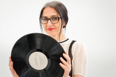 Stüdyo fotoğrafında orta yaşlı bir kadın gri saçlı, siyah beyaz giysili, plastikten plaklı beyaz elbiseli orta yaşlı, seksi bir kadın, mutlu bir hayat konsepti var.