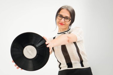 Stüdyo fotoğrafında orta yaşlı bir kadın gri saçlı, siyah beyaz giysili, plastikten plaklı beyaz elbiseli orta yaşlı, seksi bir kadın, mutlu bir hayat konsepti var.