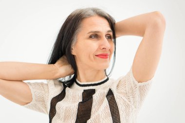 Stüdyo fotoğrafında orta yaşlı bir kadın beyaz arka planda siyah beyaz elbiseler giyerek saçlarını ağartmaya başlıyor. Orta yaşlı seksi kadın, mutlu yaşam kavramı.