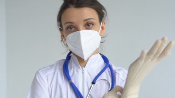 Женщина-врач откладывает защитные голубые перчатки, изолированные на белом фоне после некоторых медицинских манипуляций, вакцинации. — стоковое видео