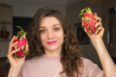 Genç kız iki taze organik ejderha meyvesi ya da pitaya, pitahaya tutuyor. Egzotik meyveler, sağlıklı beslenme konsepti