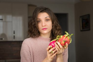 Genç kız iki taze organik ejderha meyvesi ya da pitaya, pitahaya tutuyor. Egzotik meyveler, sağlıklı beslenme konsepti
