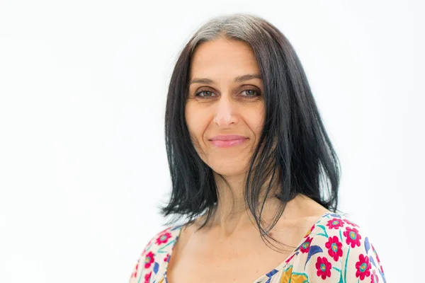 Studio photo of middle aged woman starting getting grey-haired wearing dress with flowers on white background, middle age sexy lady, cosmetology concept Stock Photo