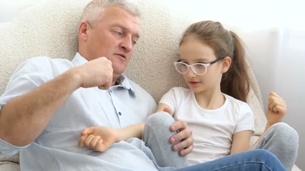 Innenporträt des grauhaarigen Vaters und des kleinen blonden Mädchens, die zu Hause miteinander spielen, Vatertagskonzept. — Stockvideo