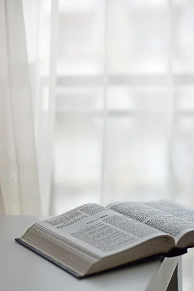 Open Bible next to the window — Stock Photo, Image