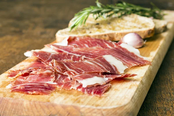 Spanish ham with toasts as background — Stock Photo, Image