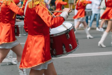 Geçit töreninde kırmızı üniformalı genç kız davulcu. Sokak performansı davulcuların yürüyüş kırmızı kostümlü kızlar şehir caddesinde