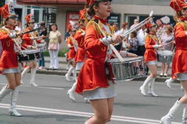 Ternopil, Ukrayna 2 Temmuz 2021: Geçit töreninde kırmızı üniformalı genç kız davulcu. Sokak performansı. Majorette 'lerin geçit töreni