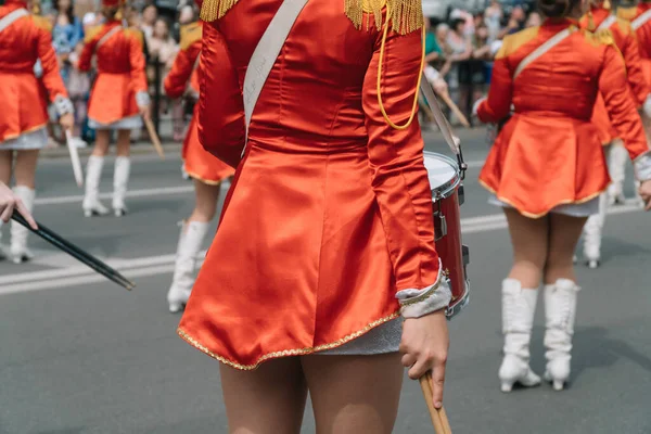 Уличное представление праздничного марша барабанов девушек в красных костюмах на городской улице. Барабанщица в красной винтажной форме на параде — стоковое фото