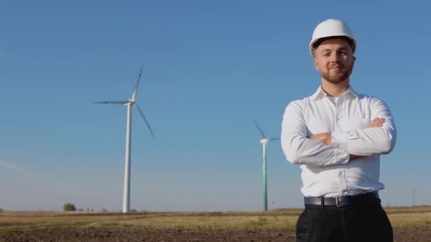 Air power engineer si trova in abiti in stile business e casco bianco su uno sfondo di mulino a vento — Video Stock