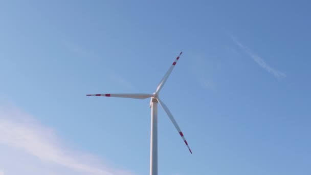 Großaufnahme einer Windkraftanlage, die sich vor hellblauem Himmel im Hintergrund dreht. Ökostrom — Stockvideo