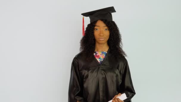 Μια νεαρή Αφρο-Αμερικανίδα με μαύρη ρόμπα και καπέλο στέκεται ίσια και κοιτάει στην κάμερα. Πορτραίτο μισού ύψους — Αρχείο Βίντεο