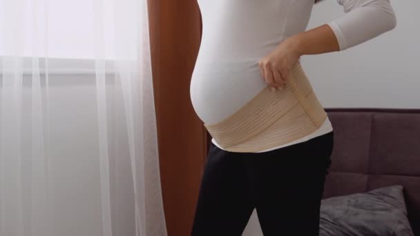 Беременная светлокожая женщина носит повязку для беременных женщин — стоковое видео