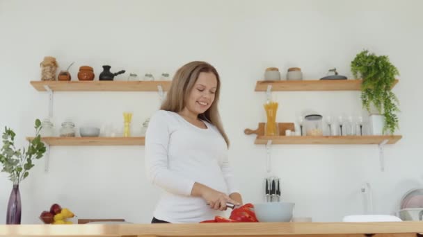 Těhotná žena v kuchyni krájí červený pepř. Zdravá vyvážená strava během těhotenství — Stock video