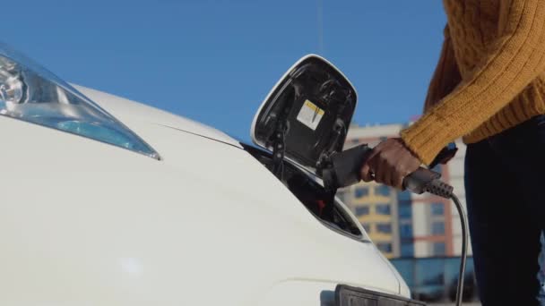 Um motorista de pele escura desconecta o carro elétrico do sistema de energia — Vídeo de Stock