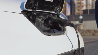 Açık tenli bir erkek sürücü elektrikli arabayı güç sisteminden ayırıyor.