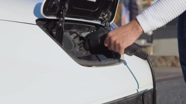 Чоловічий водій підключає електромобіль до енергосистеми для заряджання акумулятора автомобіля — стокове відео