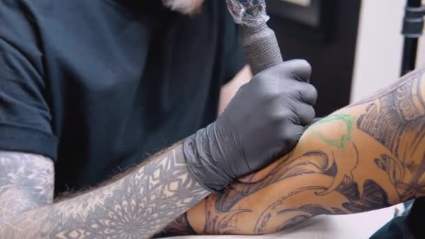 Het proces van het tatoeëren van een mans hand in een tattoo salon. Professionele tatoeage in overeenstemming met sanitaire veiligheidsnormen — Stockvideo