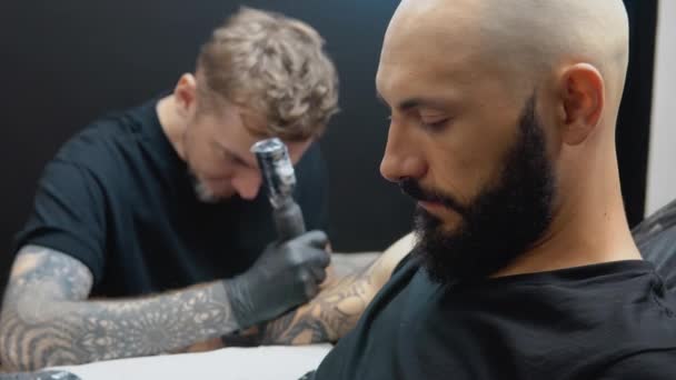 Klient siedzi na krześle, podczas gdy tatuażysta rysuje obrazek na skórze dłoni. — Wideo stockowe
