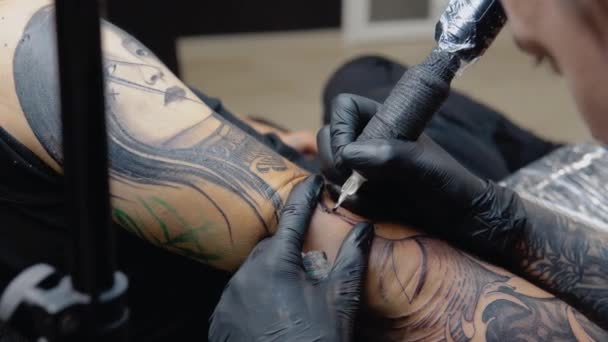 A tetoválás folyamata egy férfi kezére egy tetoválószalonban. Szakmai tetoválás az egészségügyi biztonsági előírásoknak megfelelően