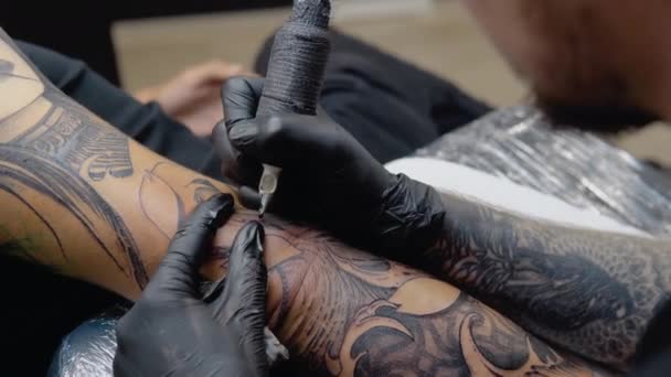 Dövmeli kollu bir sanatçı müvekkiline tam bir kol dövmesi yapar. İnsan vücudunda sanatsal kalıcı imaj — Stok video