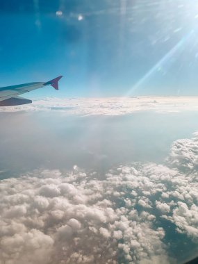 Cloudscape against blue sky through air plane window. Airplane in air with blue clouds. Airplane window