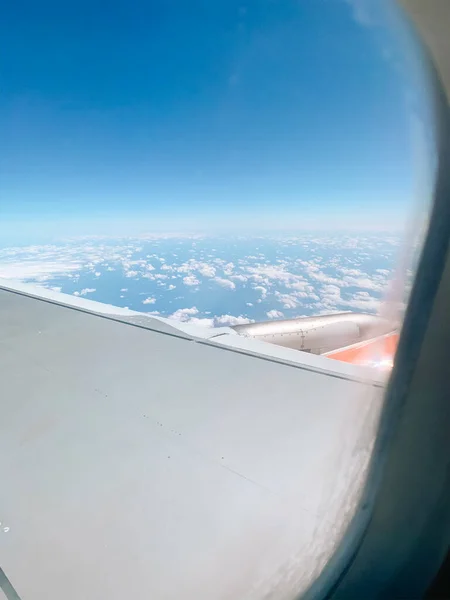 Літак у повітрі з блакитними хмарами. Вікно літака. Подорожі — стокове фото