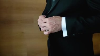 A successful young man puts on a suit black jacket. Businessman puts on a black jacket. A man buttoning his jacket, closeup