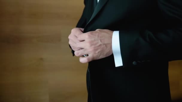 A successful young man puts on a suit black jacket. Businessman puts on a black jacket. A man buttoning his jacket, closeup — Stockvideo
