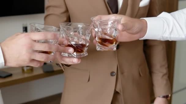 Pria tangan memegang gelas cognac, brandy, close-up. Perusahaan teman-teman duduk, berbicara, memegang dan dentingan gelas minuman wiski alkohol di tangan mereka — Stok Video