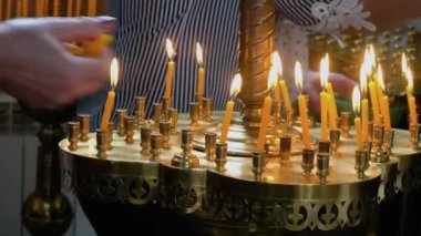 Burning candles in the Christian Orthodox Church. Woman removes burnt candles