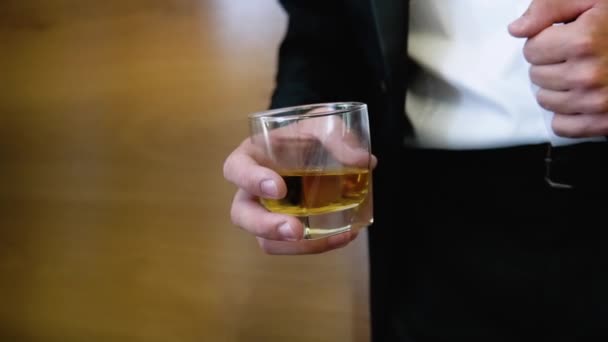 Attractive business man with a glass of whiskey in a brown room. Businessman holding whiskey — Video Stock