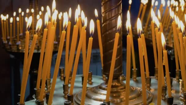 Velas encendidas en la Iglesia Ortodoxa Cristiana. Un primer plano de muchas velas enceradas arden en un candelero — Vídeos de Stock