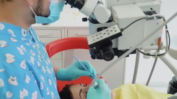 Stomatologist and patient at clinical office. A man dentist in a medical gloves works with a patient girl in a dental office. Healthcare and medicine concept. Dentistry — Stockvideo