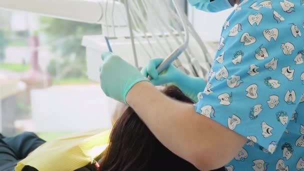 Stomatologist and patient at clinical office. A man dentist in a medical gloves works with a patient girl in a dental office. Healthcare and medicine concept. Dentistry — Stockvideo